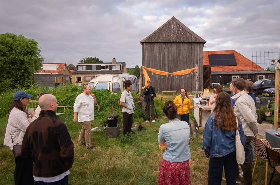 Guests gathered in the meadow in front of the old wooden barn, an orange silk swag strung across it