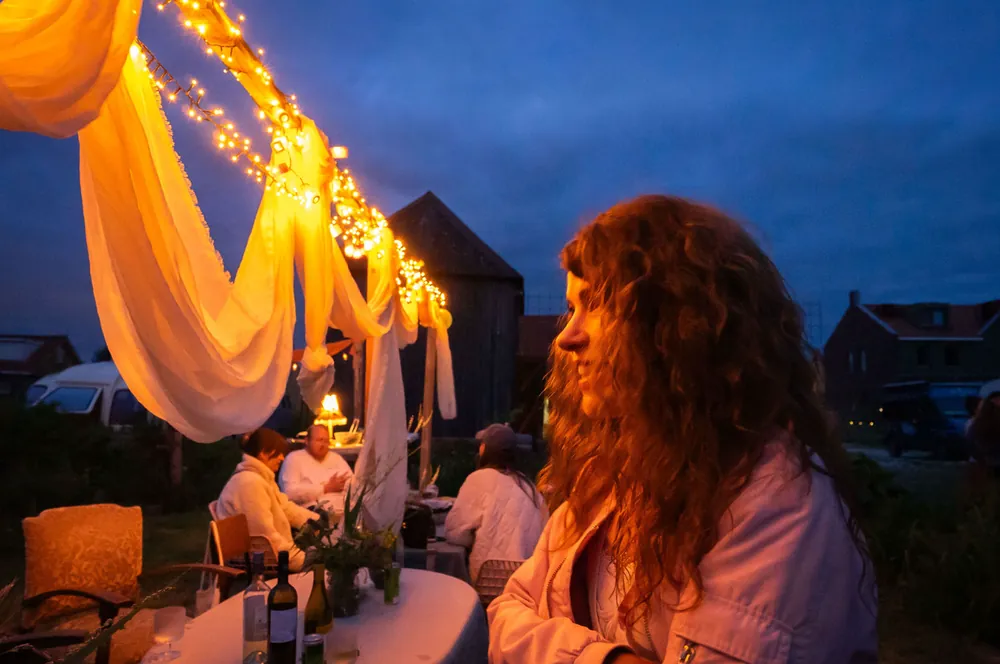 Guest in profile beside glowing linen drapes and fairy lights