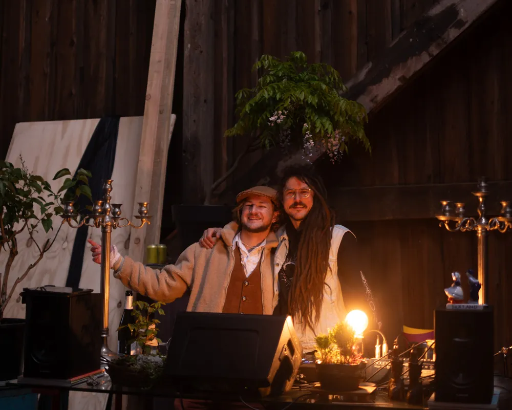 Two friends at the DJ table between candelabras in the barn